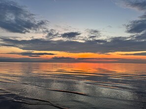A sunset over a calm sea with a clear horizon.