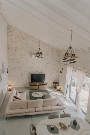 En moderne stue med sofa, fjernsyn og spisebord.