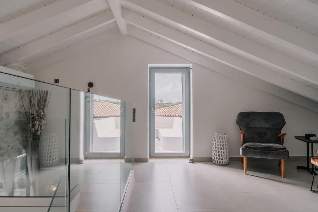 A spacious loft with a high ceiling, a large window, and a modern chair.