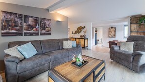 A living room with a sofa, coffee table, and wall art. - Serene Waterfront Escape With Sauna (Stavenisse)