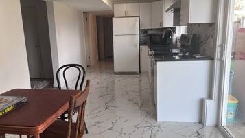 A kitchen with white cabinets, a black countertop, and a marble floor.