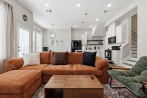 A living room with a sectional sofa, a coffee table, and a green armchair. - Unwind & Relax 20 min to Downtown HOU! (Houston)