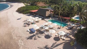 Resort à beira-mar com piscina, espreguiçadeiras e guarda-sóis.