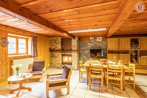 Ein gemütliches Blockhaus mit Kamin aus Stein, Holzmöbeln und Fliesenboden.