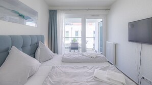 Ein Hotelzimmer mit zwei Betten, einem Fernseher und Blick auf die Straße.