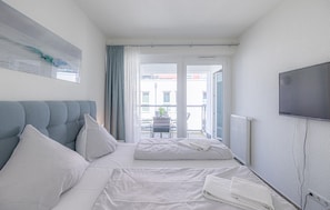 Ein Hotelzimmer mit zwei Betten, einem Fernseher und Blick auf die Straße.