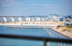 Ein Küstenhotel mit mehrstöckigen Gebäuden, einem Sandstrand und einem Felssteg.