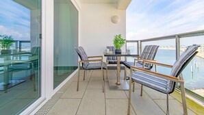 Ein Balkon mit Tisch, Stühlen und einer Pflanze in einem Topf.