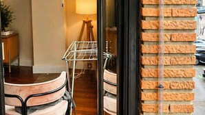 Una habitación con piso de madera, puerta de marco negro, pared de ladrillo y una ventana.
