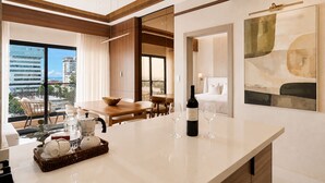 A modern hotel room with a dining area, a large window with a city view, and a wine bottle on the counter. - Niza City Tower Downtownsd Pool Gym Balcony (Santo Domingo)