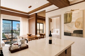 A modern hotel room with a dining area, a large window with a city view, and a wine bottle on the counter. - Niza City Tower Downtownsd Pool Gym Balcony (Santo Domingo)