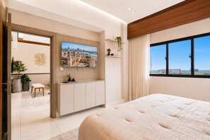 A modern bedroom with a large bed, a TV mounted on the wall, a window with a city view, and a wooden ceiling. - Niza City Tower Downtownsd Pool Gym Balcony (Santo Domingo)