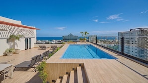 A rooftop pool with a view of the ocean, lounge chairs, and potted plants. - Niza City Tower Downtownsd Pool Gym Balcony (Santo Domingo)