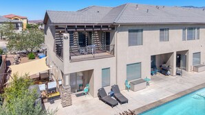 Une maison à deux étages avec une piscine, du mobilier d’extérieur et un espace barbecue.