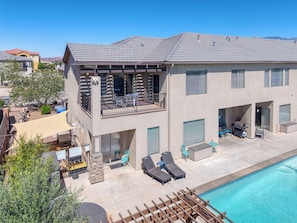 A two-story house with a pool, outdoor furniture, and a barbecue area.