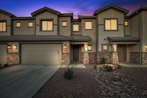 A modern two-story house with a garage, stone accents, and a well-maintained front yard.
