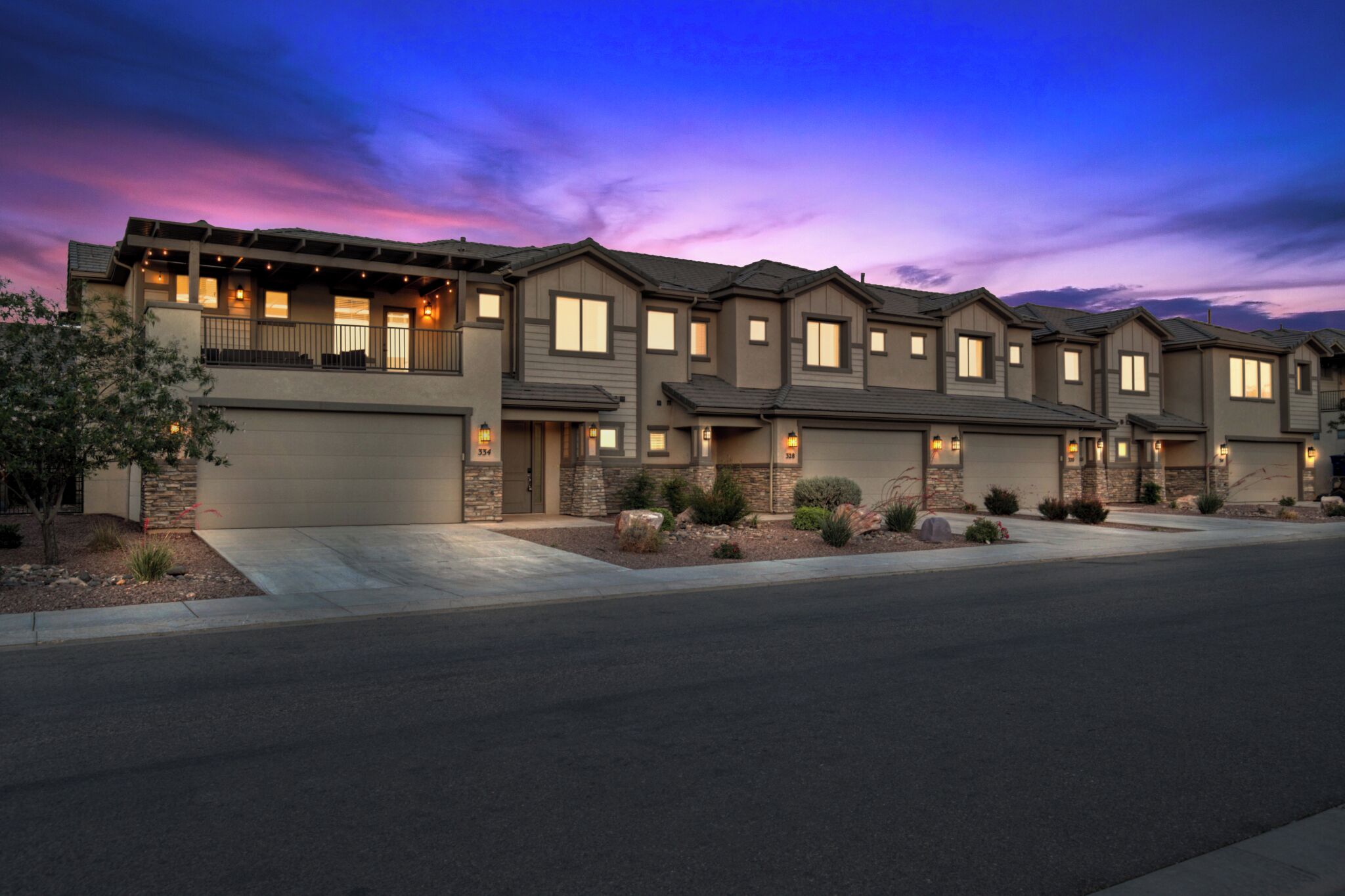 A row of modern multi-story houses with a garage, a covered patio, and a well-maintained front yard.