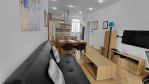 Ein modernes Wohnzimmer mit einer schwarzen Couch, einem Holzespeisetisch und einem Fernseher.