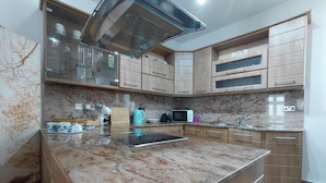 Eine Küche mit Granit Arbeitsplatte, Edelstahlgeräten, Holzschränken und einer eingebauten Mikrowelle.