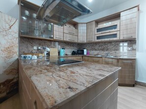 Eine Küche mit Granit Arbeitsplatte, Edelstahlgeräten, Holzschränken und einer eingebauten Mikrowelle.
