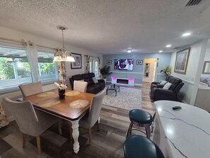 Ein modernes Wohnzimmer mit Essbereich, einem Flachbildfernseher und einer Bar.