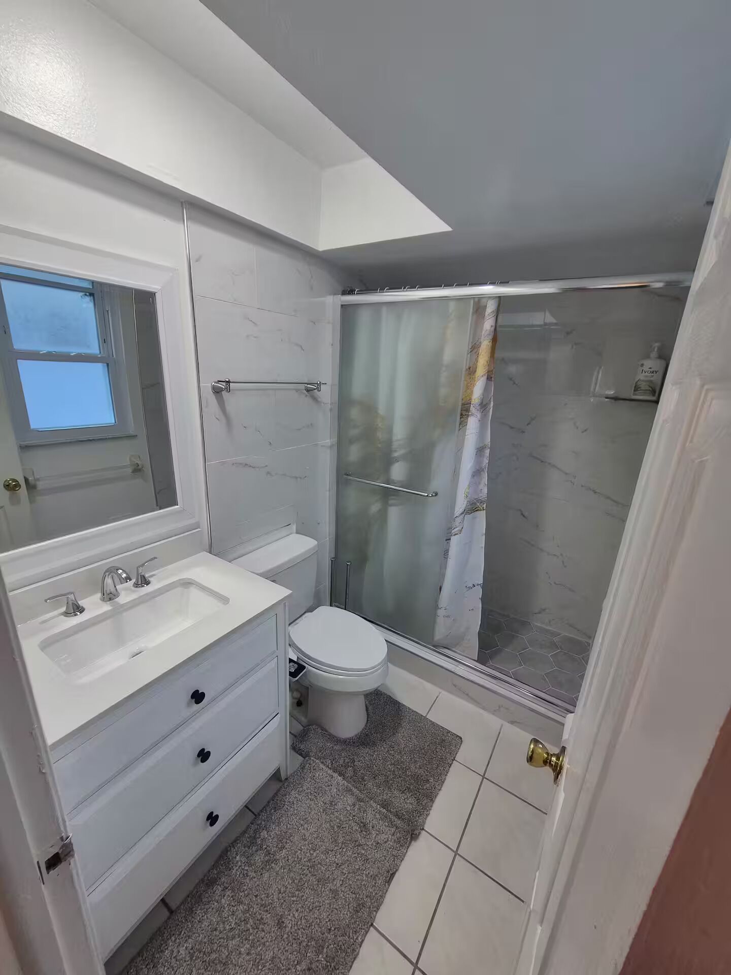Une salle de bain avec un meuble-lavabo blanc, des toilettes et une douche à parois de verre.