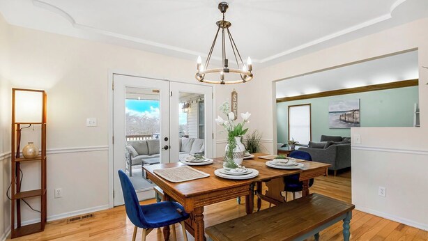 A dining area with a wooden table, blue chairs, a chandelier, and a view of the outdoors. - Beach Oasis, 4BR, Sleeps 12, Mins to Arrowhead (Raytown)