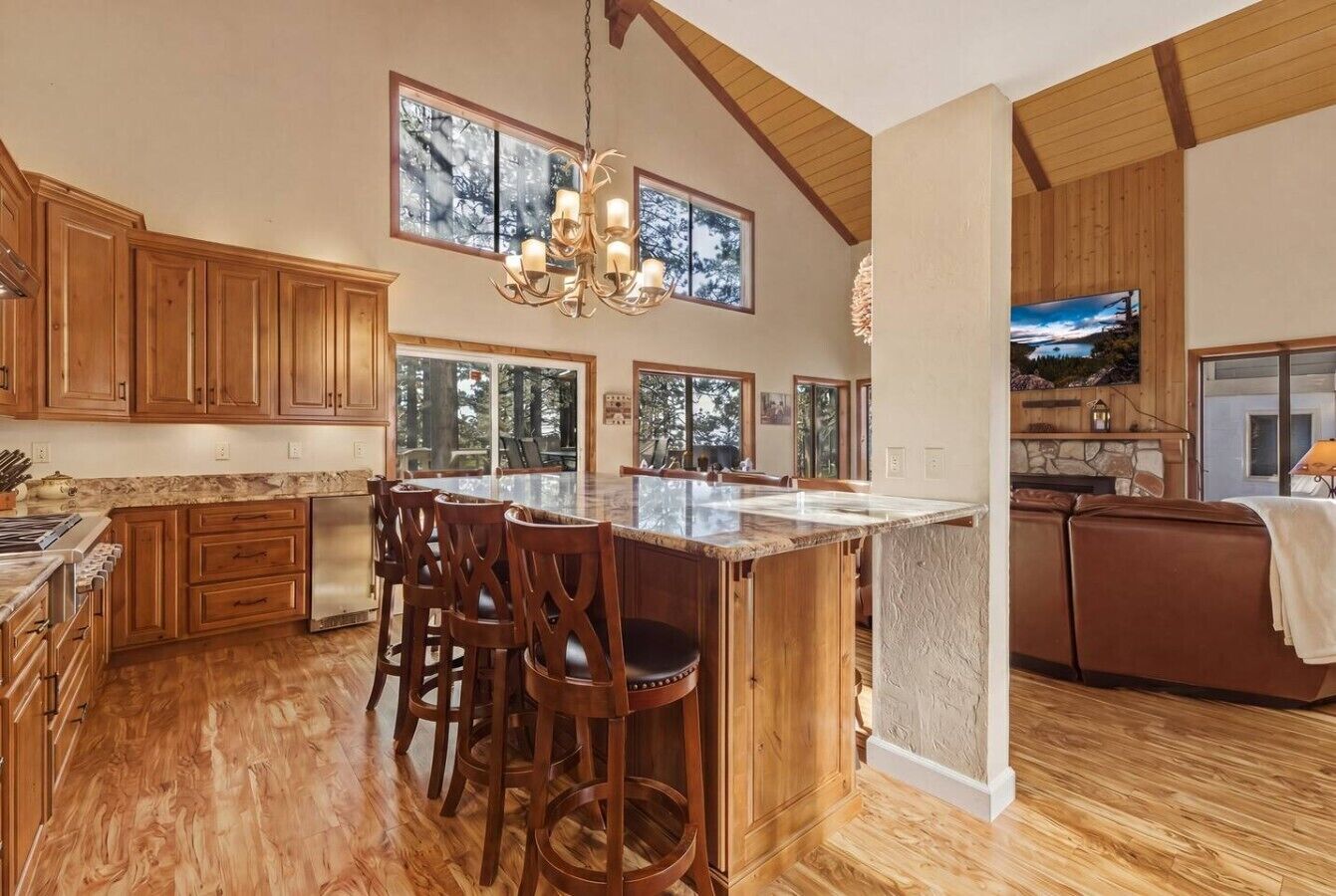A spacious kitchen with wooden cabinets, a large island with bar stools, and a dining area with a stone fireplace.