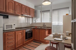 Eine Küche mit Holzausstattung, einer Mikrowelle, einem Backofen, einem Spülbecken und einem Essbereich mit Stühlen und einem Tisch.