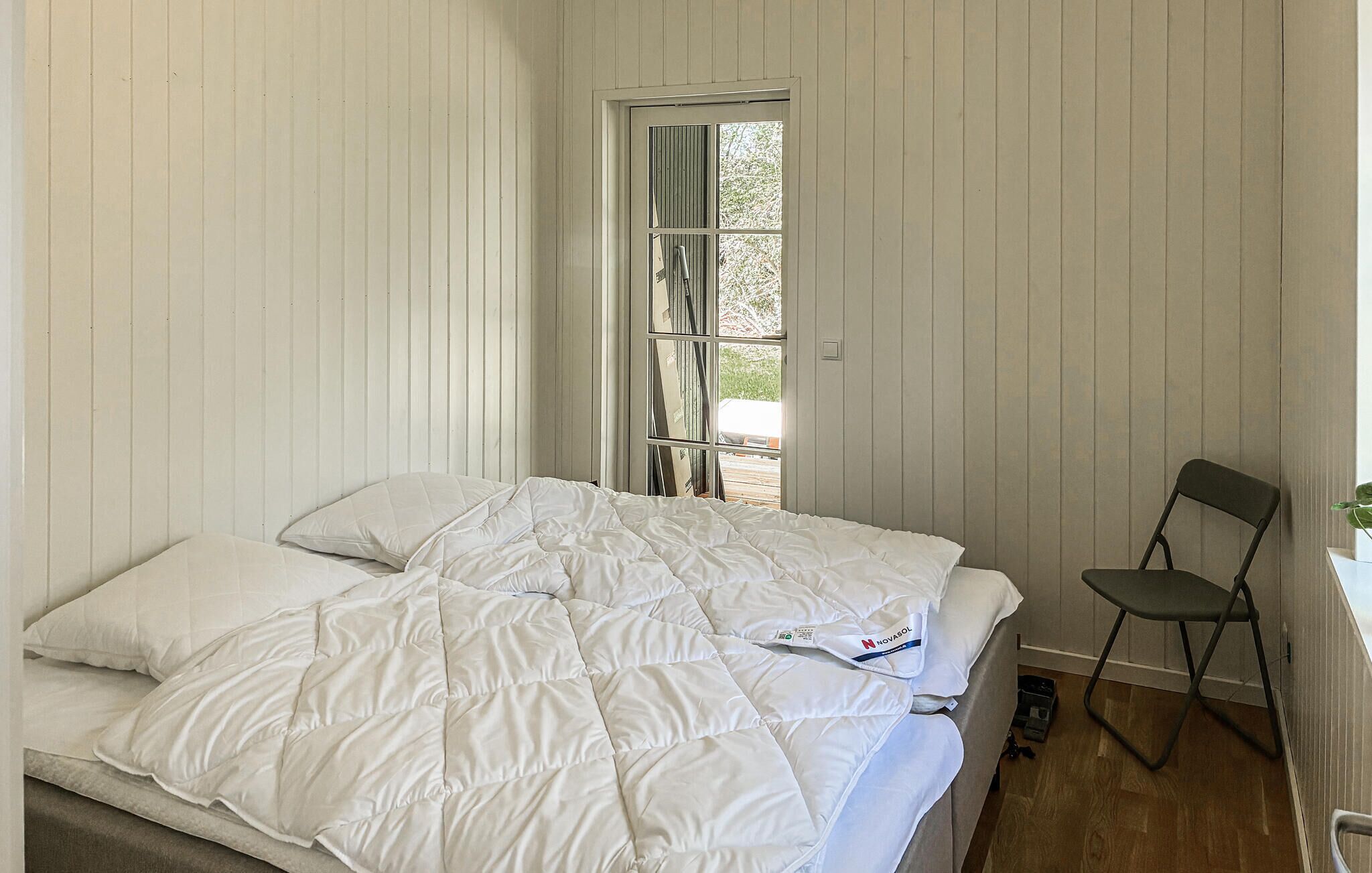 A bedroom with a bed, a chair, and a window.