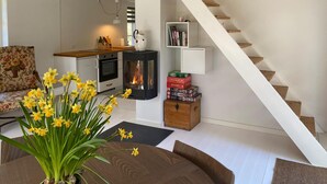 Una sala de estar con sofá, mesa de centro, chimenea, estantería y escalera.