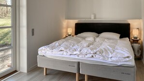 Una cama con cabecera, dos lámparas de noche y una vista a través de una ventana.