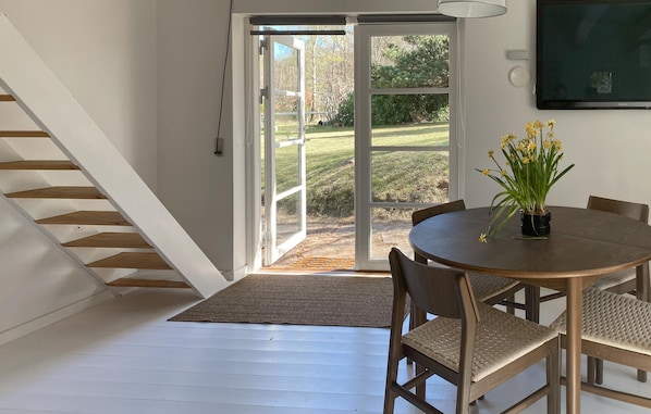 A dining area with a round table, chairs, a potted plant, and a staircase leading to a glass door. - Awesome home in Tisvildeleje with WiFi (Tisvildeleje)