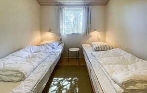A small, single-room accommodation with two beds, a window with curtains, and a small table. - Nice home in Nykøbing Sj with WiFi (Nykøbing Sj)