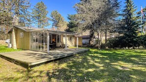 Eine Holzhütte mit Glasveranda, einer Terrasse und einer Fahnenstange.