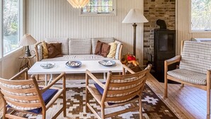 Eine gemütliche Sitzecke mit einer Couch, einem Tisch, Stühlen, einem gemusterten Teppich und einer Ziegelwand.