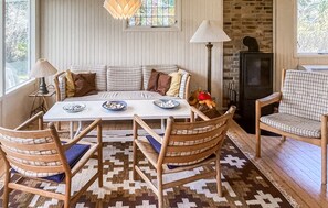 A cozy seating area with a sofa, a table, and chairs, a patterned rug, and a brick wall. - Nice home in Nykøbing Sj with WiFi (Nykøbing Sj)