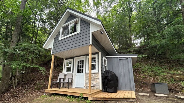 A small cabin with a porch, a covered outdoor seating area, and a shed. - Lakefront Cabin on The Big Rideau (Rideau Lakes)