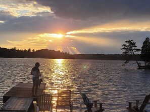 Eine Holzsteg, der sich in ein Gewässer erstreckt, mit einem Sonnenuntergang im Hintergrund.