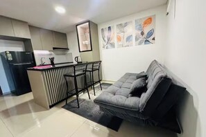 Ein kompakter Wohnraum mit Küchenzeile, einer Couch, einem Essbereich und einer Wand mit floralen Kunstwerken.