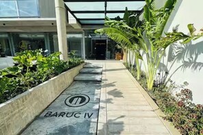 Ein Weg führt zu einem Gebäudeeingang, an dem ein Schild 'BARUC IV' steht.