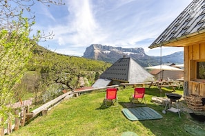 A wooden cabin with a sloped roof, a patio with red chairs, and a view of a mountain. - La Grange Caroline - ENTREMONT LE VIEUX (ENTREMONT LE VIEUX)