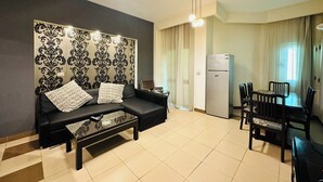 A modern living room with a sofa, coffee table, and dining area. - 02 BR apartment with full roof sea view (Red Sea Governorate)