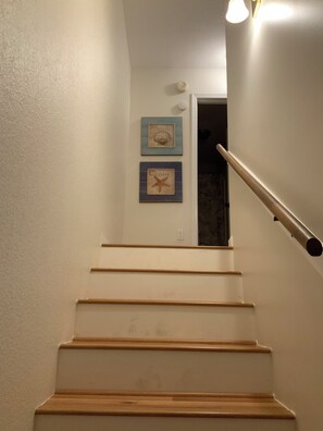 Eine Treppe mit Holzboden und einer Handläufe, die zu einer Tür mit zwei Wandbildern führt.