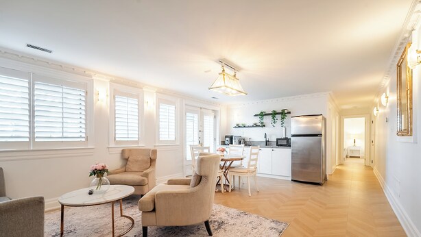 A spacious living room with a dining area, a kitchen with modern appliances, and a hallway leading to another room.