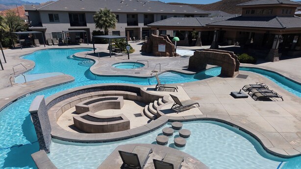 A swimming pool with multiple sections, lounge chairs, and a spa area. - 4BR Near Zion -Pool, Fire Pit & Game Room (Hurricane)