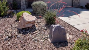 A multi-story residential building with a stone facade, a driveway, and landscaped garden with rocks and plants. - 4BR Near Zion -Pool, Fire Pit & Game Room (Hurricane)