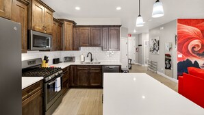 A modern kitchen with wooden cabinets, stainless steel appliances, and a large island. - 4BR Near Zion -Pool, Fire Pit & Game Room (Hurricane)