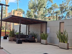 Ein Außenbereich mit überdachter Terrasse, Sofas und Pflanzgefäßen.