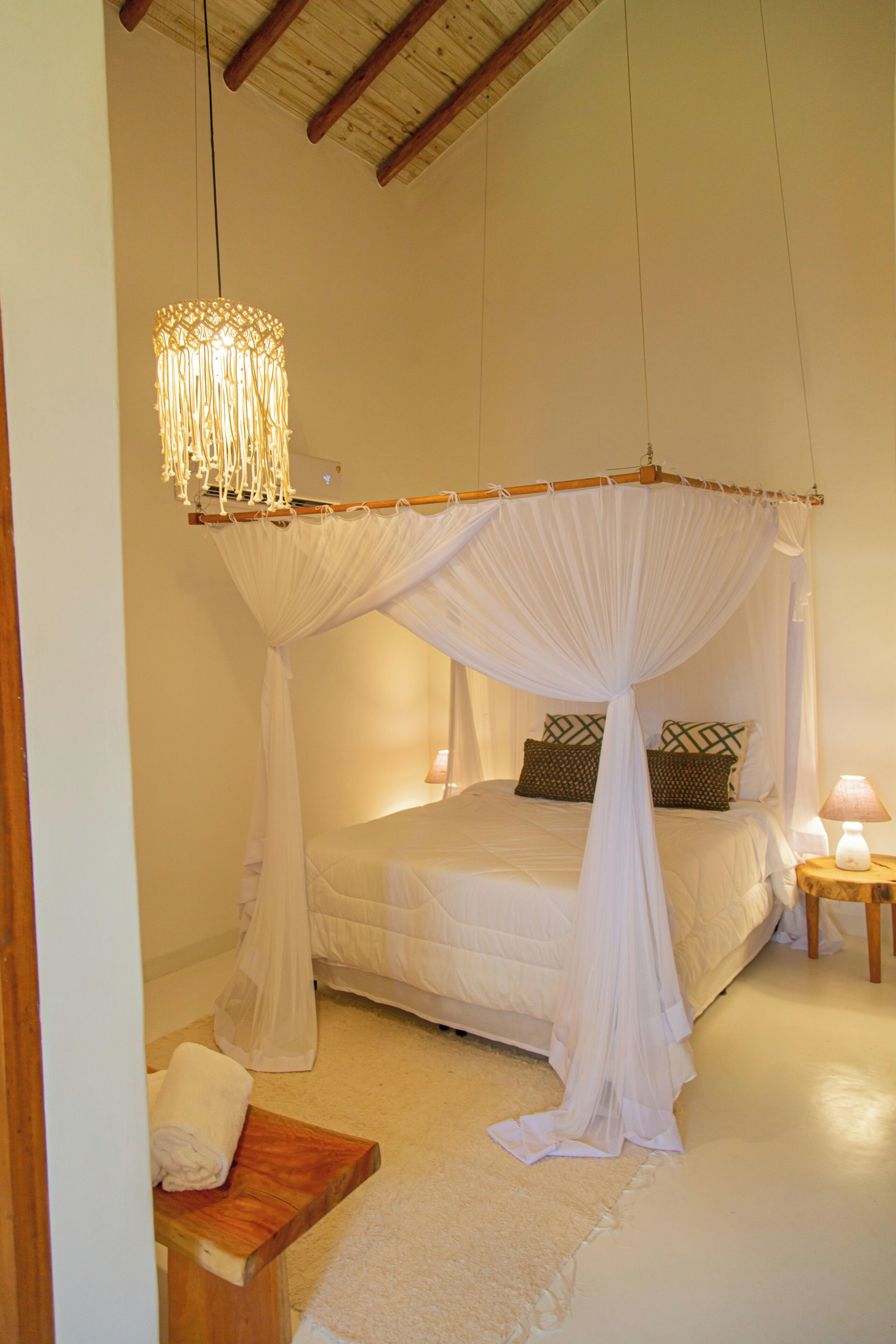 Une chambre à coucher avec un lit à baldaquin, des lampes de chevet et un banc en bois.